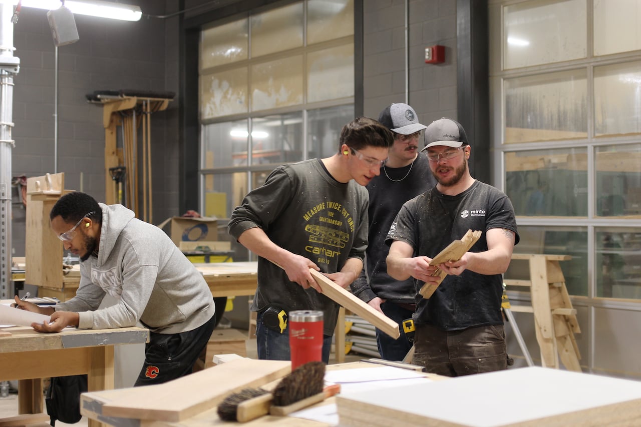 A group of carpentry students work on projects inside a carpentry lab.